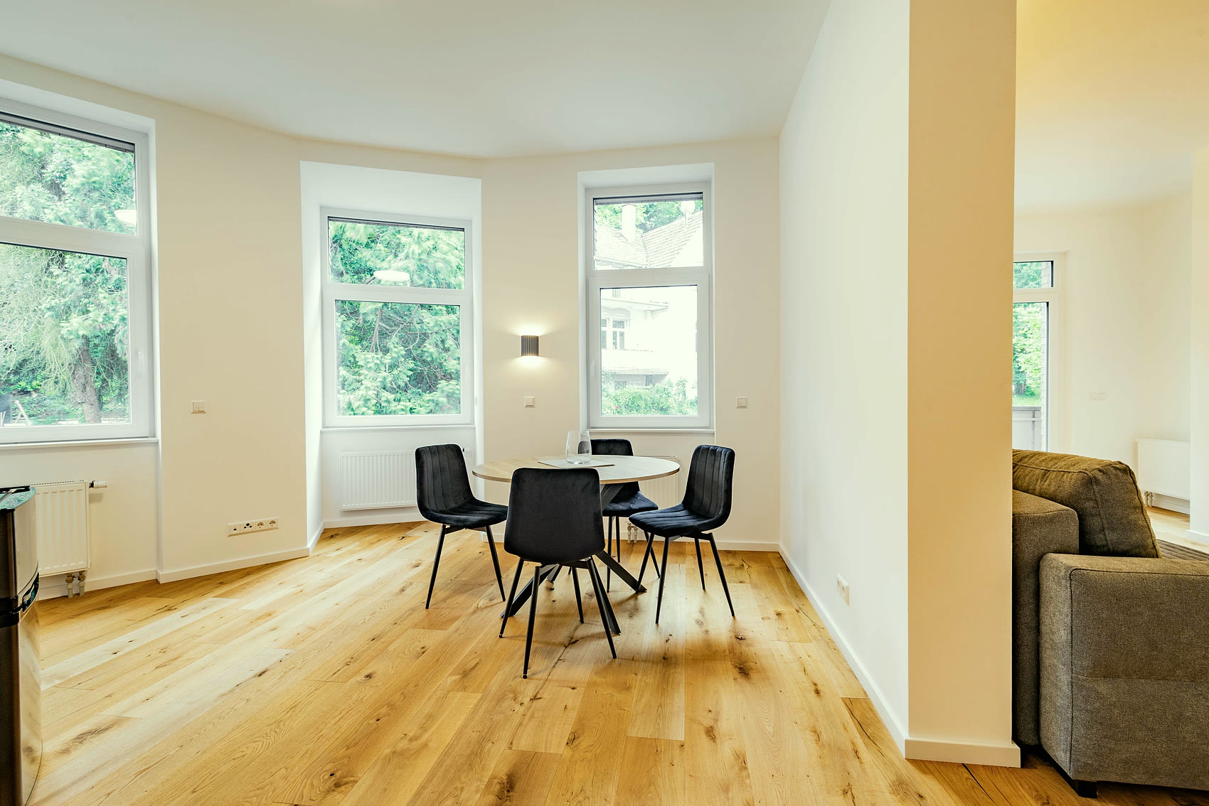 Bewohntes Apartment mit rundem Esstisch im Erker und Sofa auf Eichenparkett